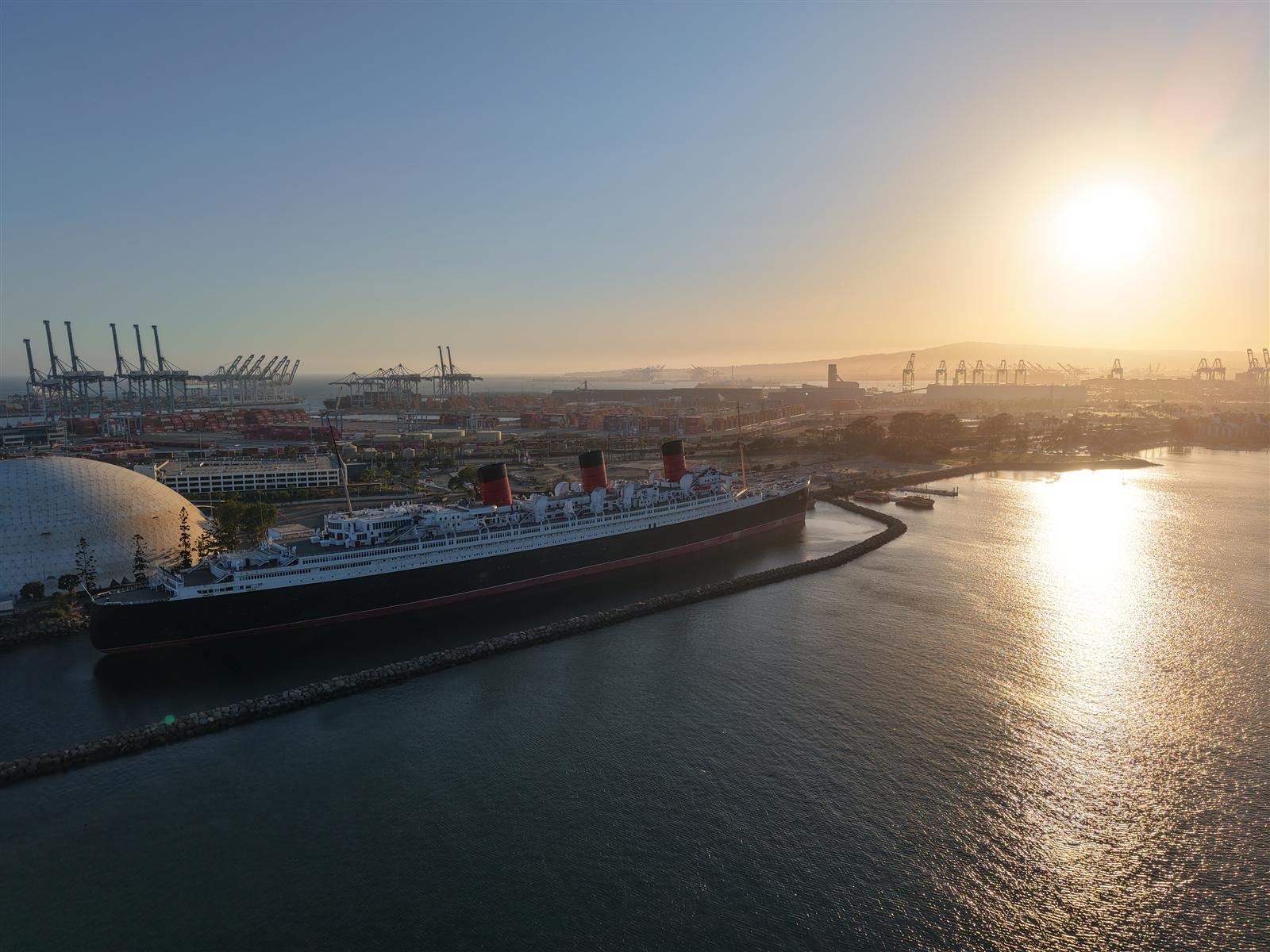 Queen Mary at Sunrise — historic ocean liner docked at Long Beach with port cranes in the background